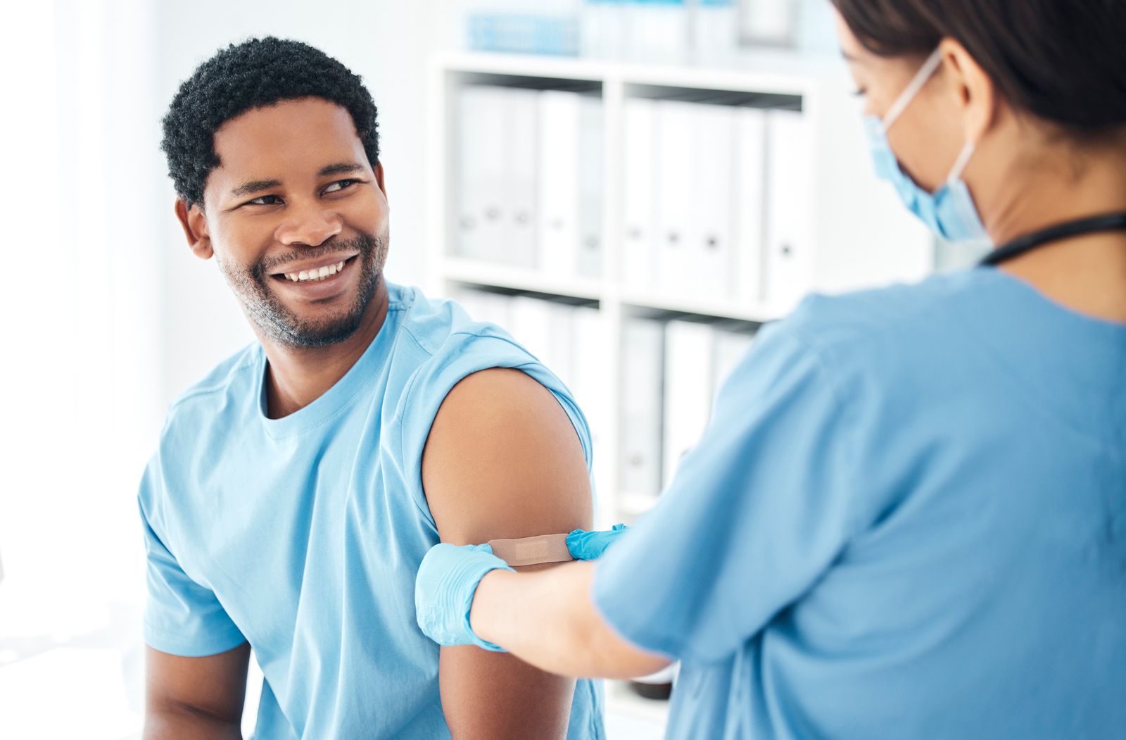 Smiling patient getting a bandage from a nurse after his flu shot