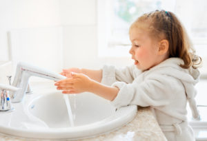 Cute little girl is washing hands under running water.